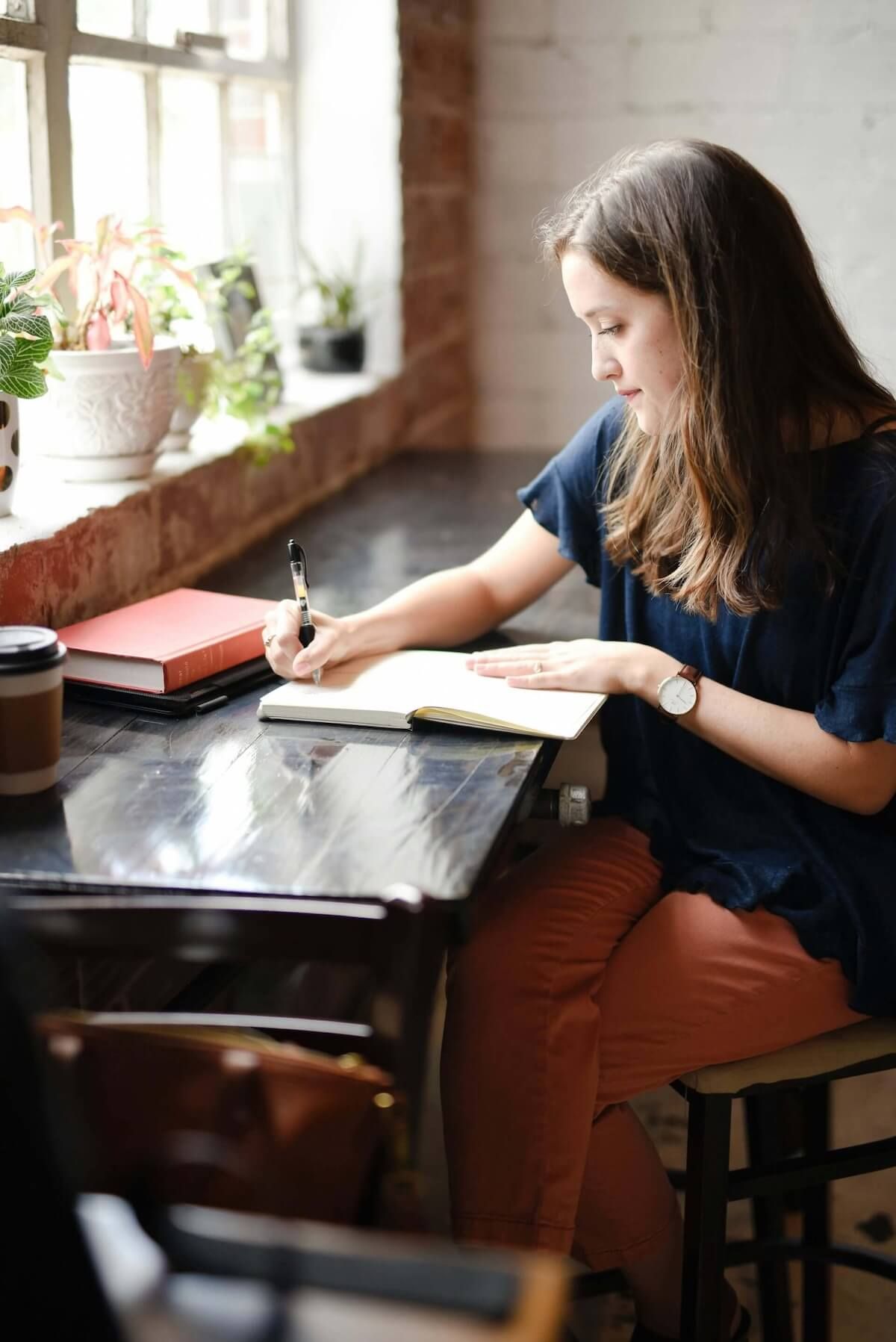 Woman writing at a table by a window